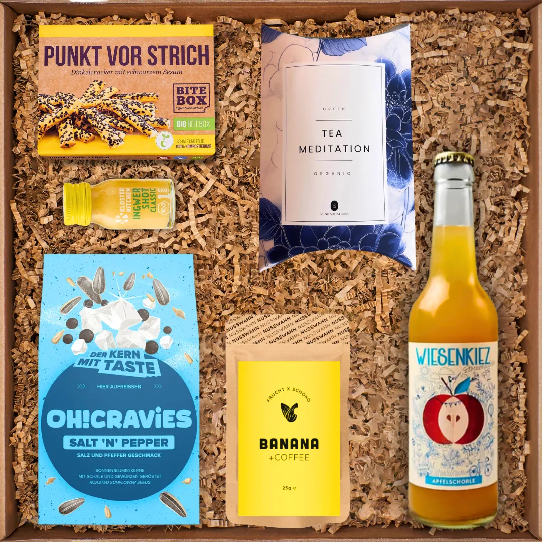 Geschenkbox mit Dinkelcracker, Ingwershot, Tee Meditation, Sunflower Snacks, Bananen-Kaffee und Apfelschorle.