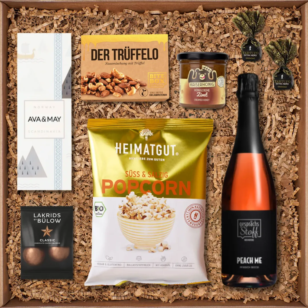 Geschenkbox mit Trüffel-Nussmischung, Duftkerze, Popcorn, Honigcreme Zimt, Lakritz, Tartufo-Pralinen und Pfirsich-Secco.