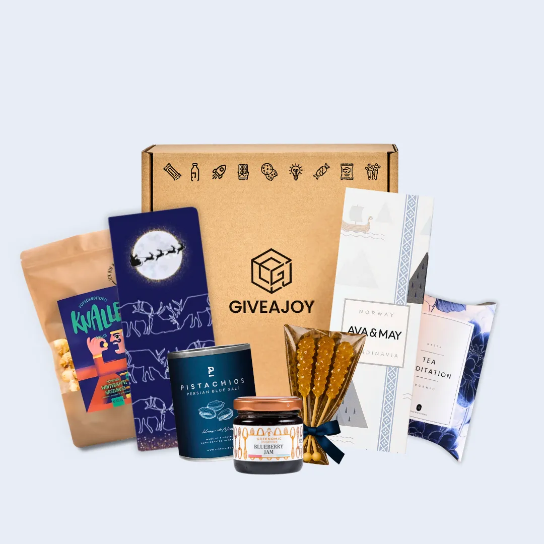 Geschenkbox mit GIVEAJOY-Logo und verschiedenen Snacks und Tees vor hellem Hintergrund.