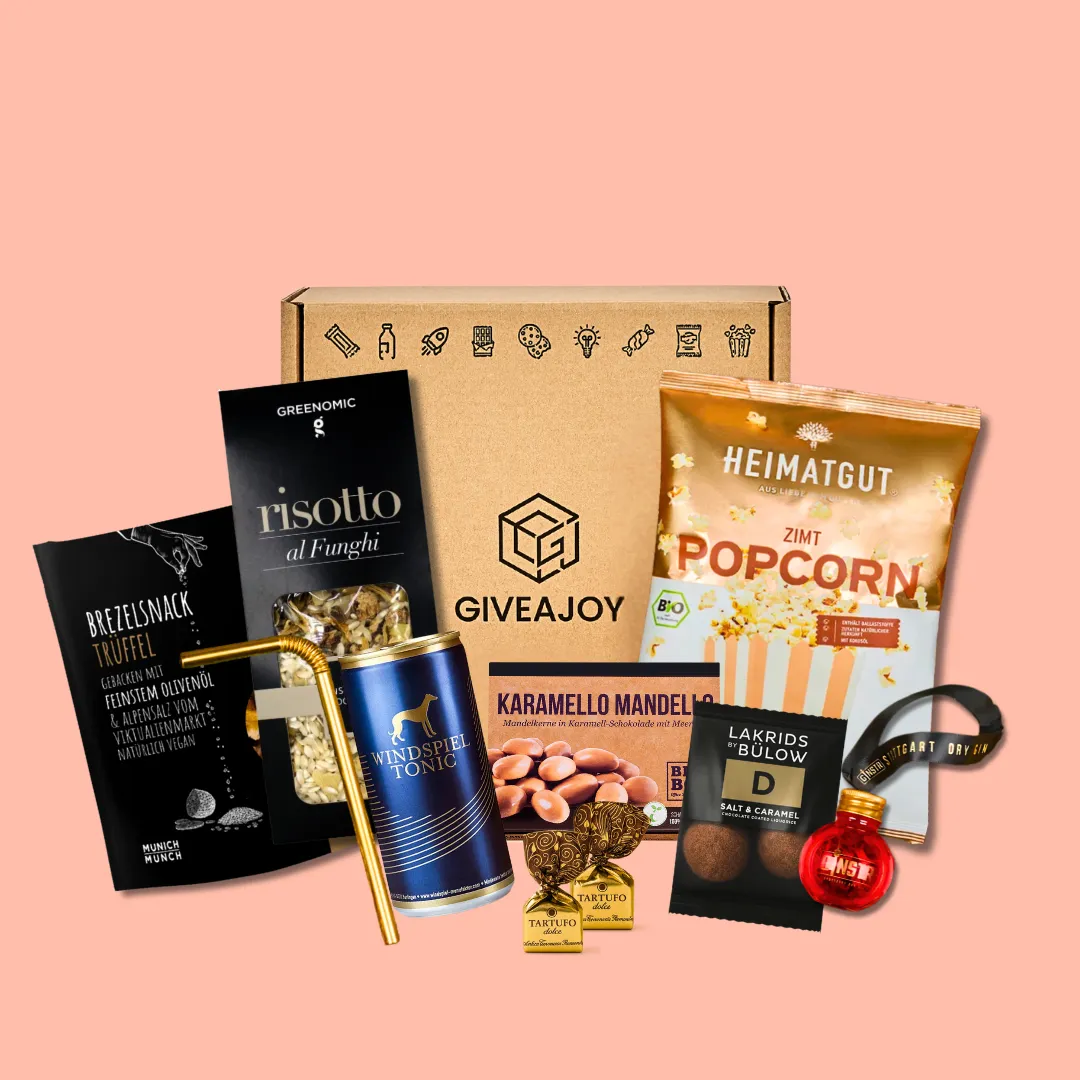 Weihnachtliche GIVEAJOY-Geschenkbox mit Snacks und Getränken auf rosa Hintergrund.