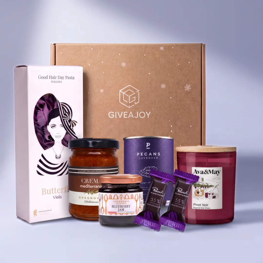 Inhalt der Weihnachtsgenuss-Box vor dem GIVEAJOY-Karton: Crema mediterranea, Blueberry-Marmelade, Pasta, Pekannüssen mit Lavendel, Duftkerze und zwei Schokoladen.