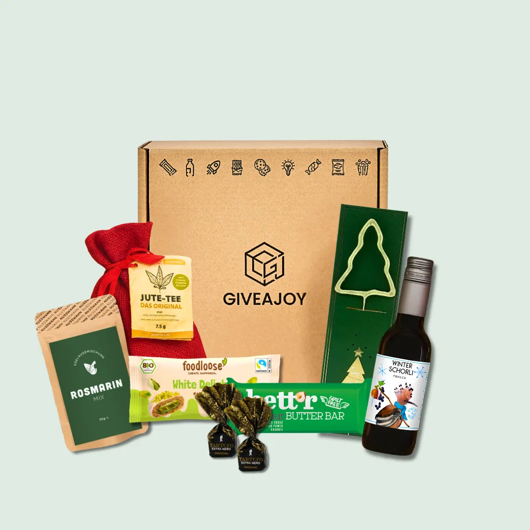 Geschenkbox mit Tee, Schokolade, Pralinen, Gewürz, Keks, Saft und rotem Beutel auf hellgrünem Hintergrund.