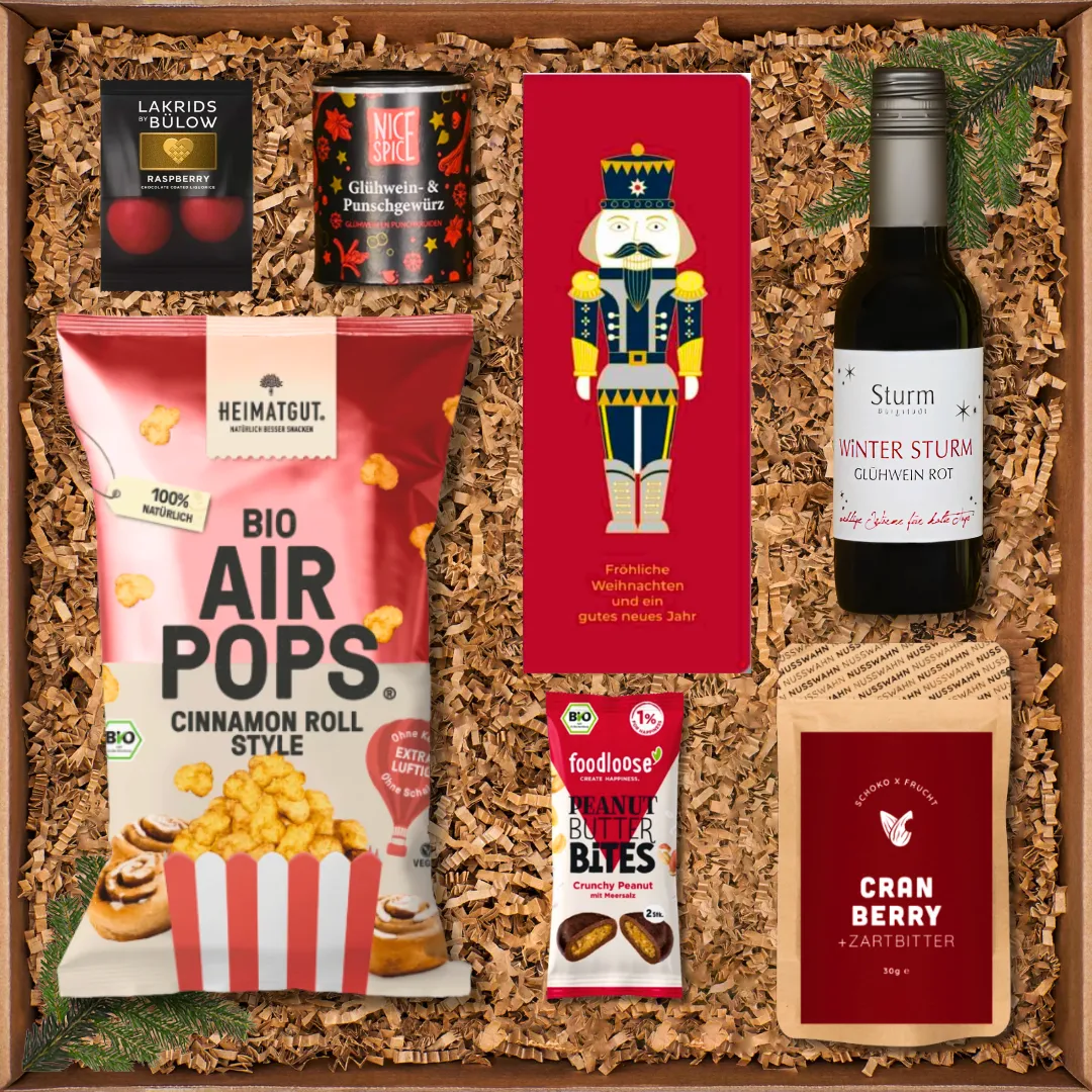 Geschenkbox mit Weihnachtsleckereien: Glühwein, Gewürze, Snacks, Schokolade, Popcorn und Nussriegel.