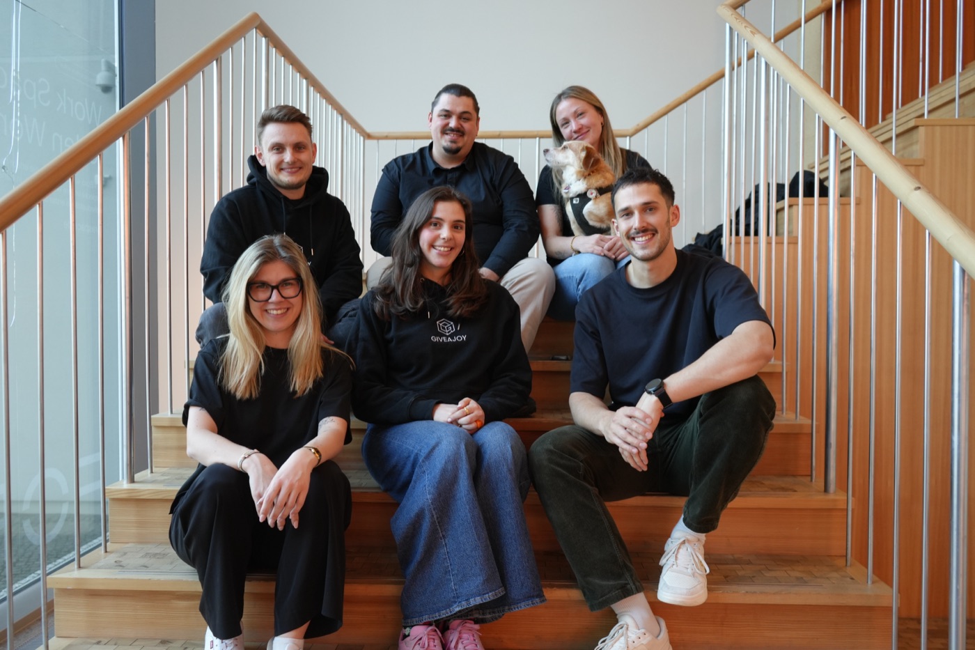 Das GIVEAJOY-Team auf einer Treppe im Büro – die Menschen, die die Beratung machen.